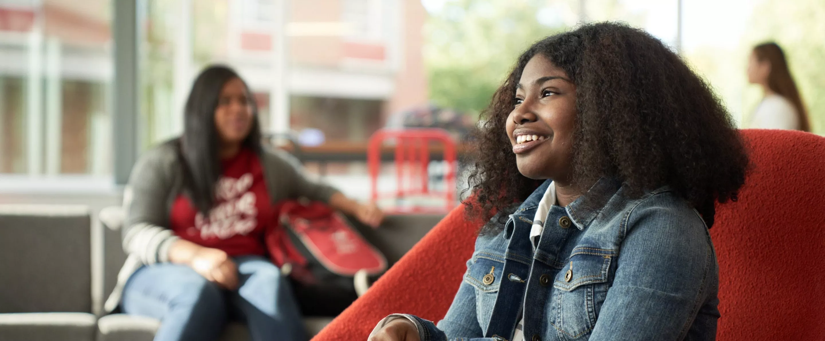 Student, Idaya Gager, sits in a red chair as she poses for campaign.