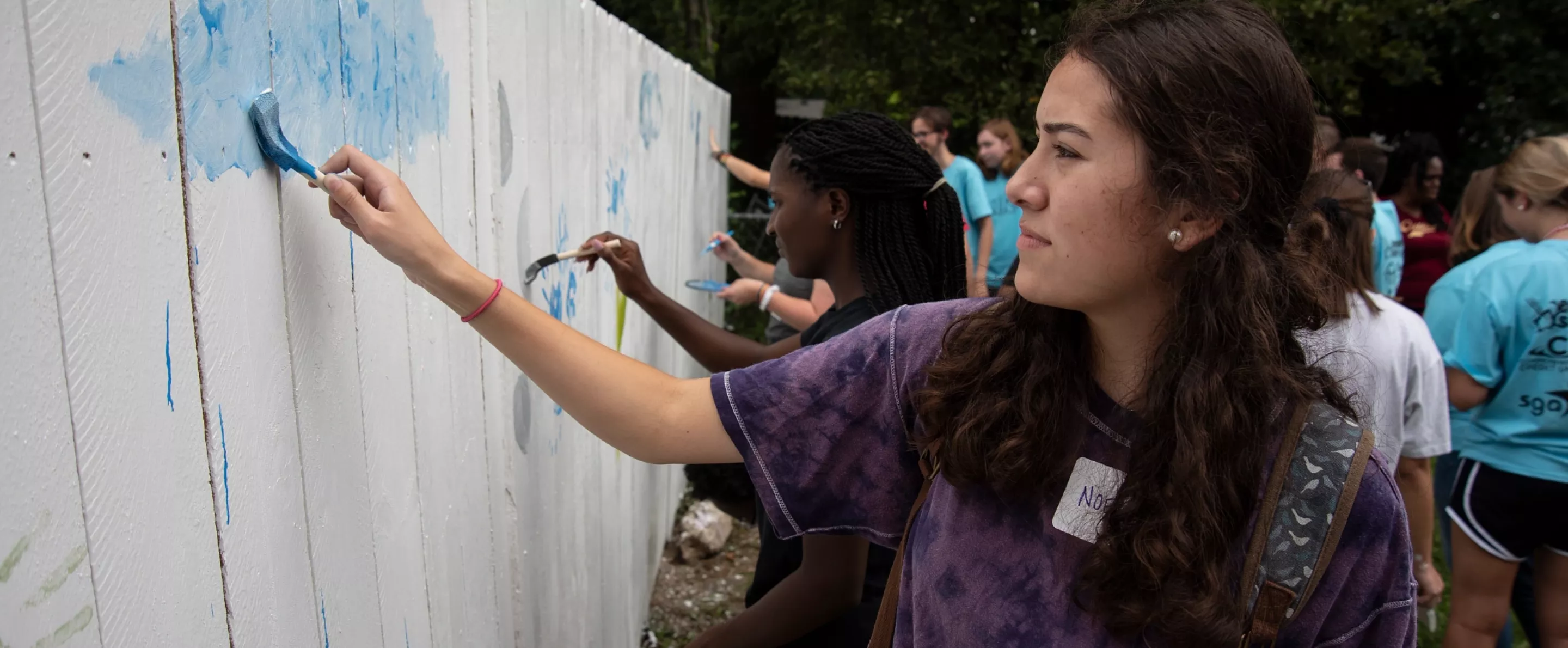 Students with SOUL work together to paint a fence