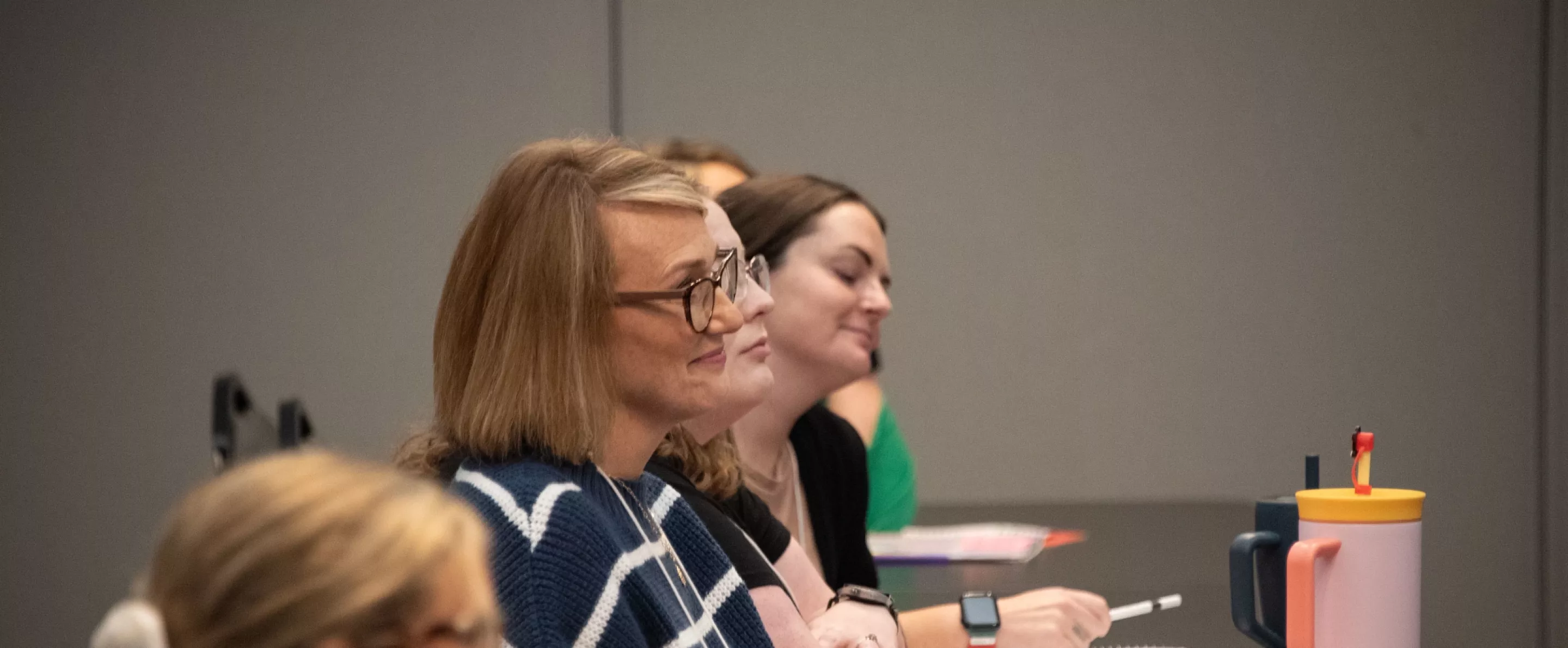 Participant smiling while engaged listening to presenter at Autism Educator Institute