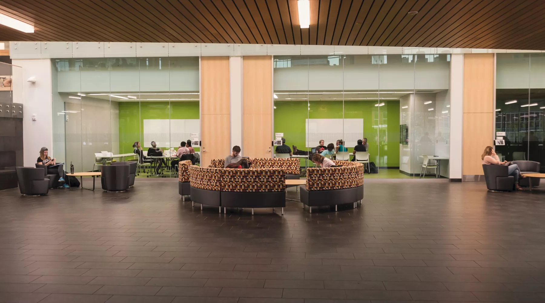 Students relaxing in a common area and conference room in the Belknap Academic Classroom Building