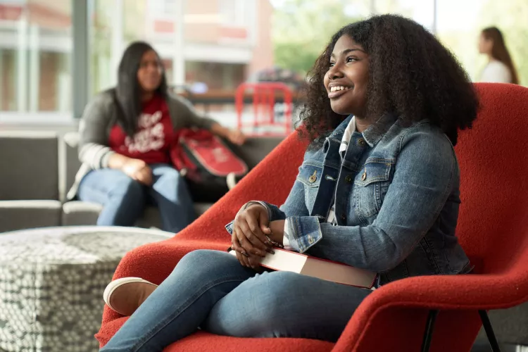 Student, Idaya Gager, sits in a red chair as she poses for campaign.