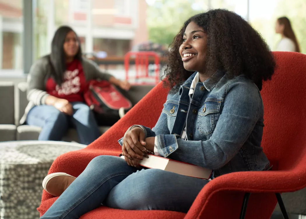 Student, Idaya Gager, sits in a red chair as she poses for campaign.